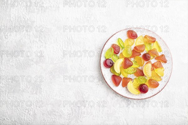 Various fruit jelly candies on plate on gray concrete background. top view, flat lay, copy space