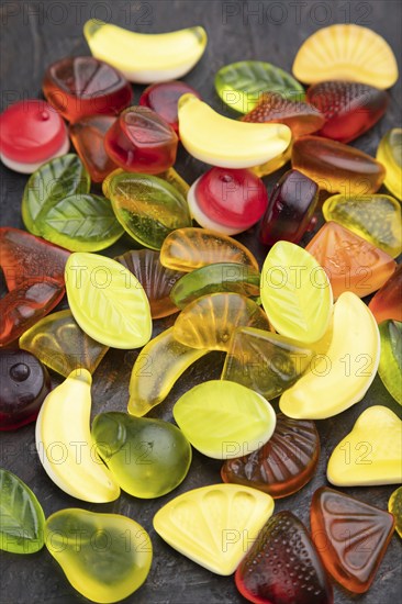 Various fruit jelly candies on black concrete background. side view, close up