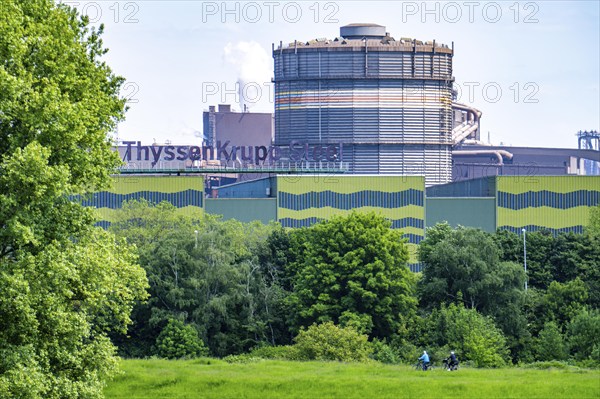 The ThyssenKrupp Steel steelworks in Duisburg-Beeckerwerth, cyclists on the Rhine dyke, green Rhine meadows Landscape, North Rhine-Westphalia, Germany, Europe