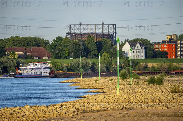 Cargo ship at low water on the Rhine near Duisburg-Homberg, view of Duisburg-Laar, houses on Deichstraße, gasometer of ArcelorMittal Hochfeld GmbH steel wire plant, 3.48 metres is normal, at the time of the photo only 2.58 metres level, but still far from the low level when restrictions for shipping enter, North Rhine-Westphalia, Germany, Europe