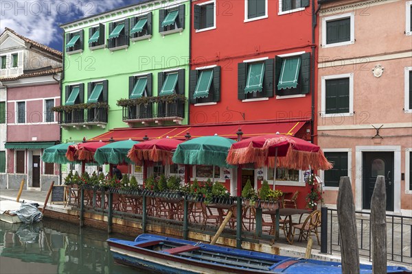 Colourful houses and colourful parasols in a restaurant on the canal, Burano, Venice, Veneto, Italy, Europe