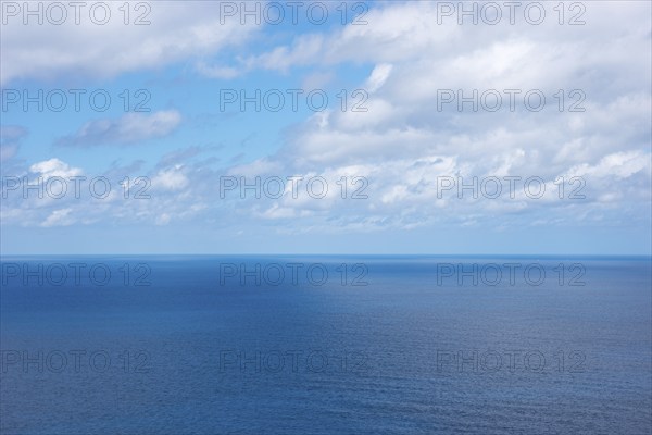 Calm, wide blue sea under a clear blue sky with scattered white clouds, distant horizon in spring, spring, tiny sailboats and a distant ship on the horizon, Mediterranean Sea on the northwest coast, Majorca, Spain, Europe