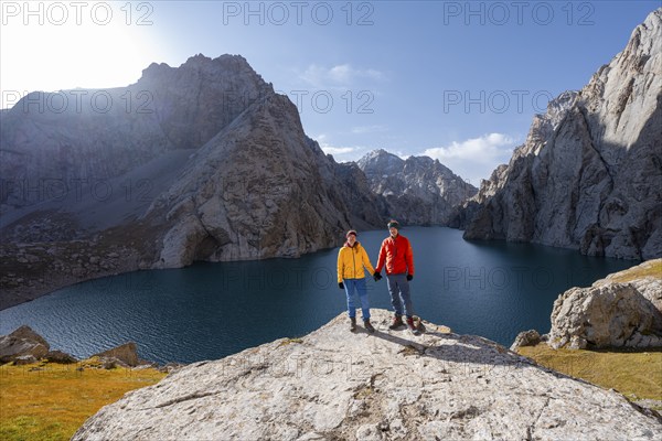 Couple at the blue mountain lake between rocky steep mountain peaks, Kol Suu Lake, Sary Beles Mountains, Naryn Province, Kyrgyzstan, Asia