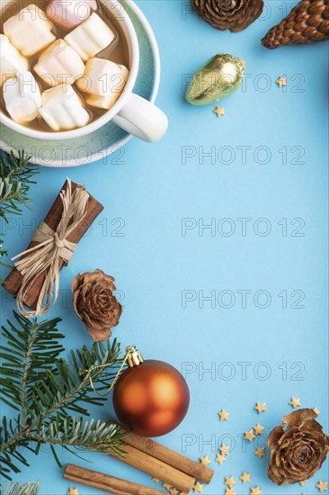 Christmas or New Year composition. Decorations, box, cinnamon, cones, fir and spruce branches, cup of coffee, on a blue paper background. Top view, copy space, flat lay