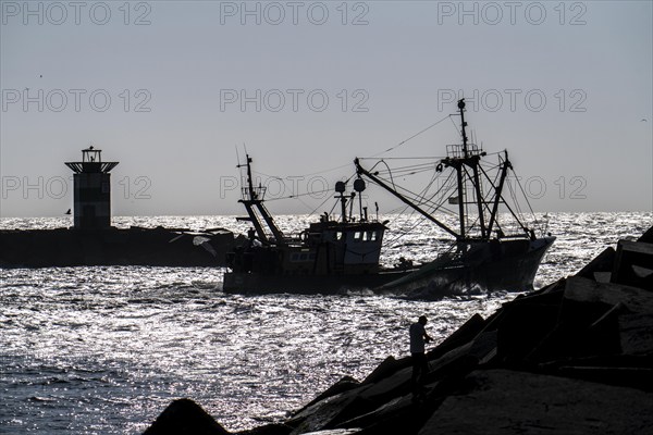 Fishing vessel TH10 DIRKJE, off the coast of Scheveningen, The Hague, with spread nets, beacon of the harbour exit, Netherlands