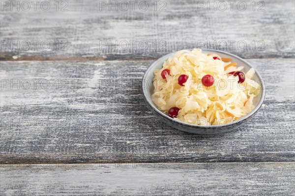 Sauerkraut, marinated cabbage on a blue ceramic plate on a gray wooden background. Side view, close up, copy space