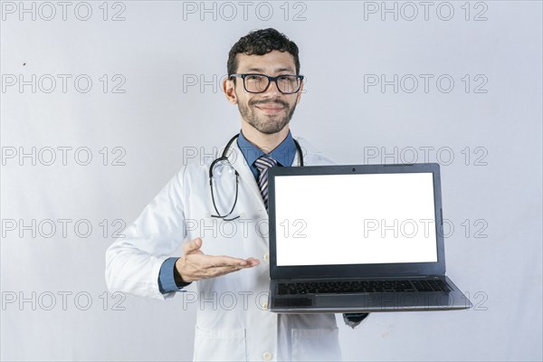Smiling doctor showing laptop screen isolated. Handsome doctor pointing at laptop screen isolated