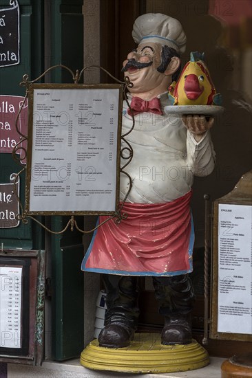 Cooking figure with fish in front of a restaurant, Burano, Veneto, Italy, Europe