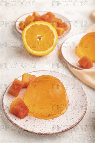Papaya and orange jelly on gray concrete background and orange linen textile. side view, flat lay, close up