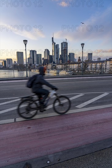 Skyline of the city centre of Frankfurt am Main, cyclist on the Ignatz-Bubis-Bridge, dusk, river Main, winter, Hesse, Germany, Europe