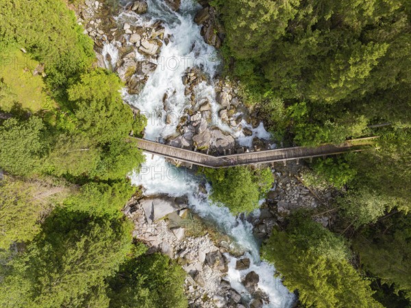Aerial view of a wooden bridge over a raging river, surrounded by dense forest, Zillertal, Austria, Germany, Europe