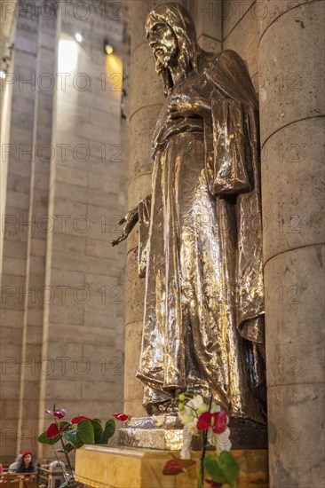 Metal statue in a church, surrounded by flowers, shown in architectural detail, Paris