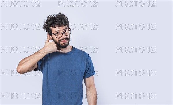 Attractive young man imitating telephone conversation isolated. Young man in glasses making calling gesture isolated