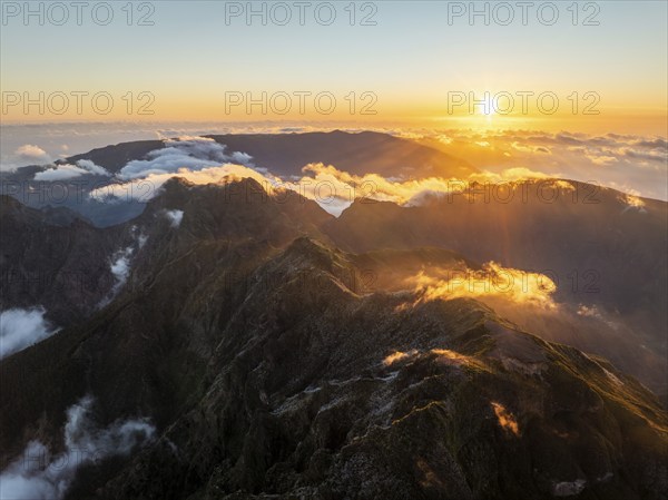 Aerial drone view of mountains over clouds near Pico Ruivo on sunset. Madeira island, Portugal, Europe