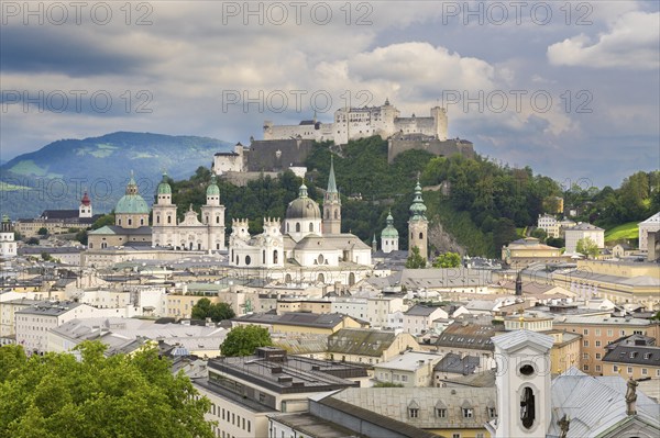 View of Salzburg with Hohensalzburg Fortress in the background and the historic city centre in the foreground, surrounded by mountains under a cloudy sky, Salzburg, Salzburger Land, Austria, Europe