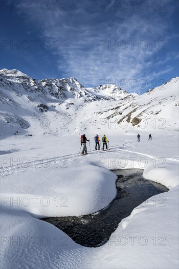 Small stream in a snow-covered mountain landscape, ski tourers in a valley, ascent to the Madritschspitze, Ortler Alps, Vinschgau, Italy, Europe