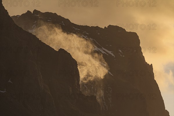 The spray of a waterfall sprays upwards, strong wind, mountains, morning light, backlight, East Iceland, Iceland, Europe