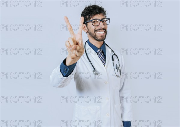 Doctor counting number two isolated. Smiling young doctor counting number 2 on isolated background