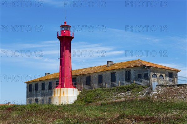 Red lighthouse next to a building in a coastal landscape with blue sky, Farol de Esposende in front of the fort of Sao Joao Baptista de Esposende at the mouth of the river Cavado, Esposende, União das Freguesias de Esposende, Marinhas e Gandra, Norte, Portugal, Europe