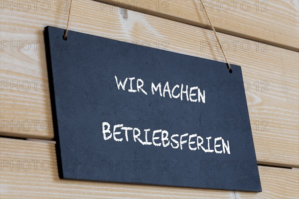Symbolbild für Betriebsferien: Schild auf einer Holztafel mit der deutschen Aufschrift WIR MACHEN BETRIEBSFERIEN