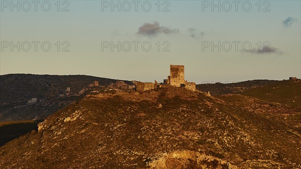Wide view of an old castle in the mountains, illuminated by the last rays of the setting sun, residential tower on a mountain, Mani peninsula, Peloponnese, Greece, Europe