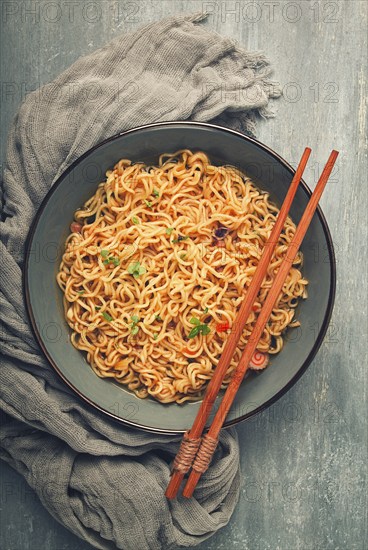 Instant noodles, in a bowl, on a gray table, top view, no people