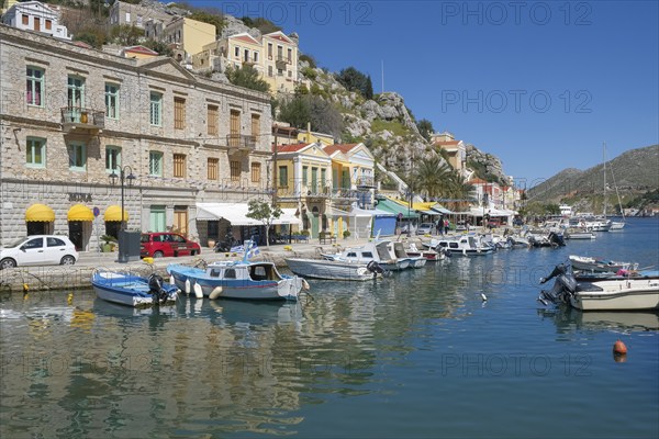 Waterfront promenade and boats in the harbour of Symi town, Symi island, Dodecanese, Greek islands, Greece, Europe