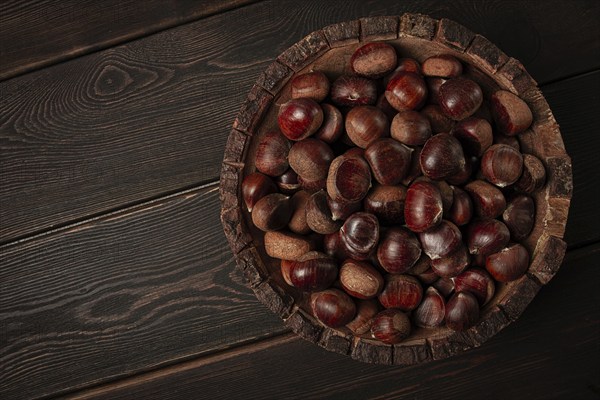 Fresh chestnuts, in a wooden bowl, top view, no people