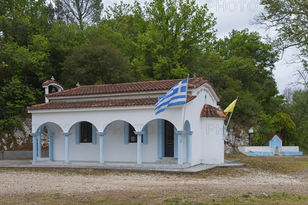 Small Greek church in a rural setting with flags and surrounding trees, located on the 77, island of Euboea, Central Greece, Greece, Europe