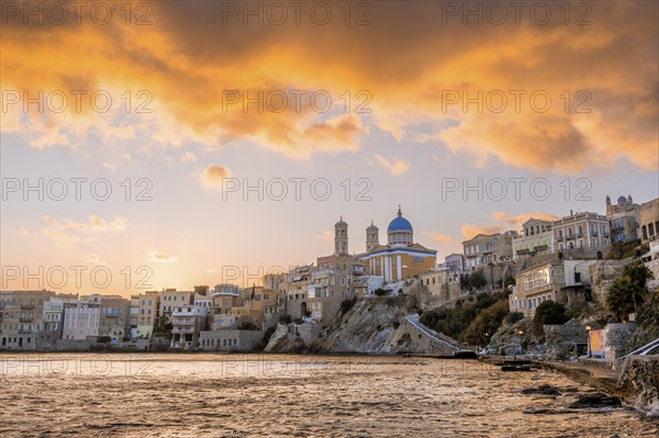 View of the village with the Greek Orthodox church of Agios Nikolaos, Asteria Beach, at sunset with atmospheric clouds, Ermoupoli, Syros, Cyclades, Greece, Europe