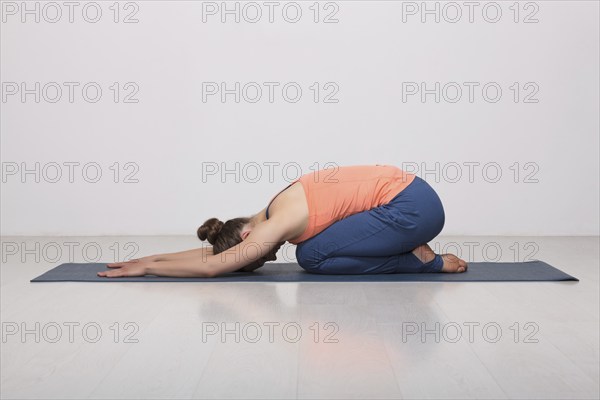 Beautiful sporty fit yogini woman practices yoga asana balasana (child's pose), resting pose or counter asana for many asanas in studio