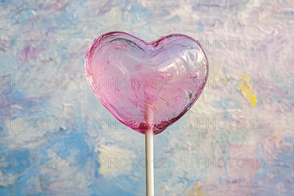 Pink heart shaped Valentine's Day lolli in front of colorful background, AI generated