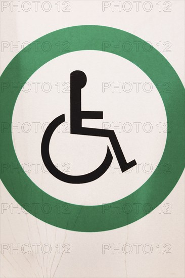 Close-up of posted white metal with black wheelchair in green circle Reserved Handicap Parking Spot pictogram notice sign outdoors, Quebec, Canada, North America