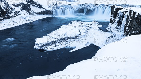 Ice layer in the river Skialfandaljot, behind it the waterfall Godafoss, Northern Iceland Eyestra, Iceland, Europe