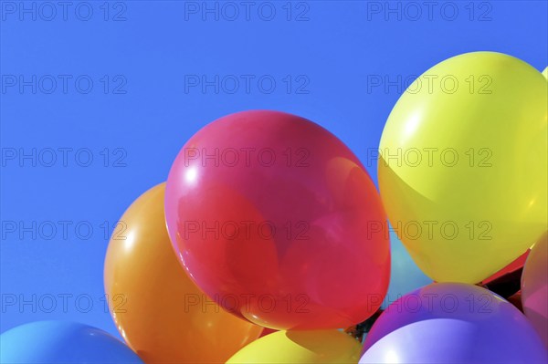 Close-up of colourful balloons against a blue sky