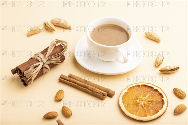 Composition with almonds, cinnamon and cup of coffee on orange pastel background. Blank, side view, still life, close up