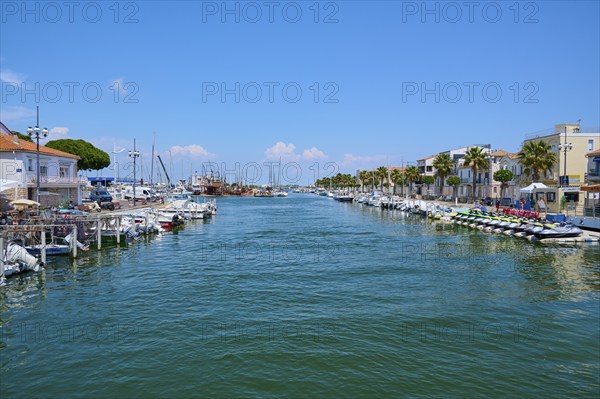 Coastal town with colourful houses and palm trees, boats in the water, on a sunny day, summer, Le Grau-du-Roi, Gard, Mediterranean, France, Europe