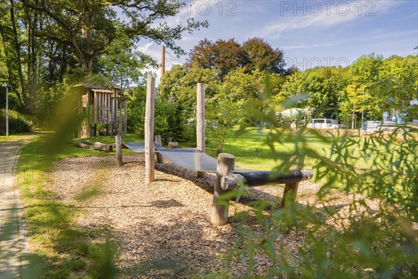 Wooden bridge on a playground surrounded by lush greenery and clear blue sky, Nagold, Black Forest, Germany, Europe