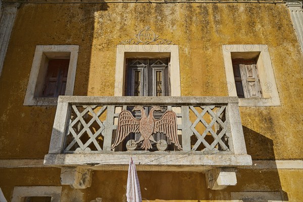 Traditional building with balcony and eagle motif, characterised by yellow colour, Colourful mountain village, Morning light, Olymbos, Karpathos, Dodecanese, Greek Islands, Greece, Europe