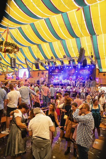 Large crowd celebrates in front of a stage in a festively decorated marquee, Canstatter Wasen, Stuttgart, Germany, Europe
