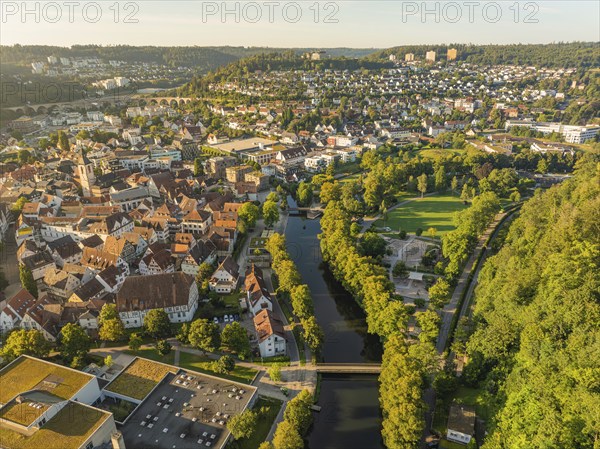 Wide aerial view of a town with a river, bridge and many houses surrounded by green hills, Nagold, Black Forest, Germany, Europe