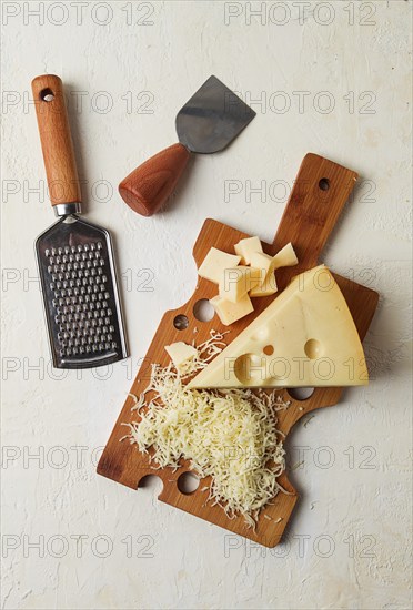 Grated cheese, Maasdam, on a cutting board, grater and cheese knife, close-up, no people