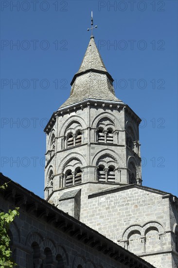 Orcival. Bell tower of the Notre-Dame d'Orcival basilica showcasing Romanesque architecture under a clear blue sky, Puy de Dome, Auvergne-Rhone-Alpes, France, Europe