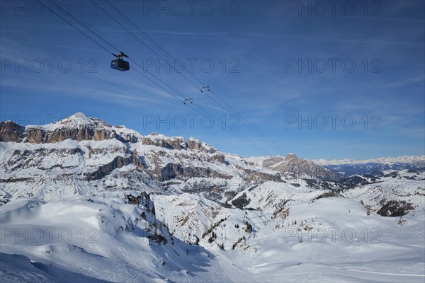 View of a ski resort piste with people skiing in Dolomites in Italy with cable car ski lift. Ski area Arabba. Arabba, Italy, Europe