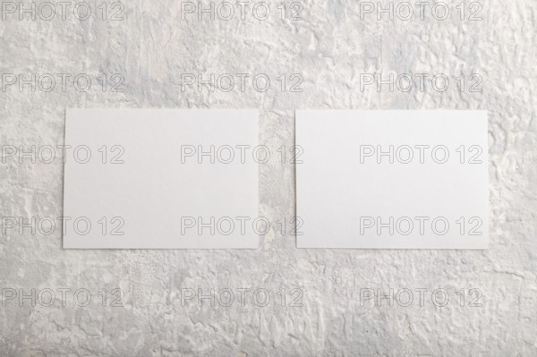 White paper business card, mockup on gray concrete background. Blank, flat lay, top view, still life, copy space