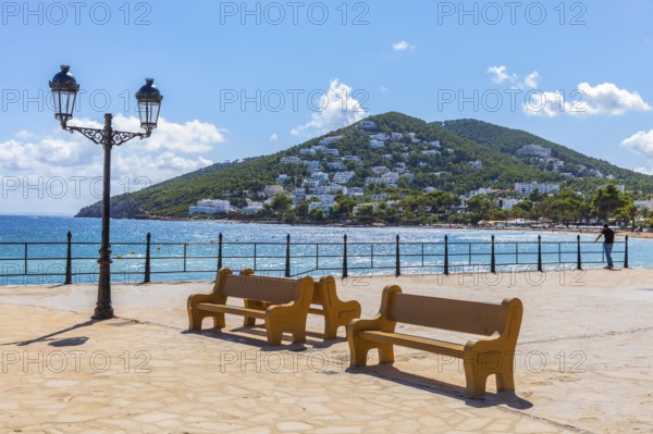 Large square at the harbour of Santa Eularia des Rui with lantern and benches, behind the peninsula La Siesta with holiday homes, Ibiza, Balearic Islands, Mediterranean Sea, Spain, Europe