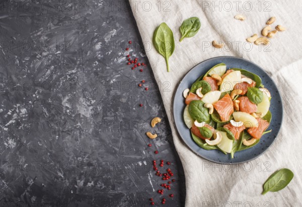 Fresh salmon with pineapple, spinach and cashew on a black concrete background. Top view, copy space, flat lay, linen tablecloth