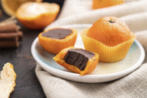 Truffle chocolate tangerine candies on a black concrete background and linen textile. Side view, close up, selective focus