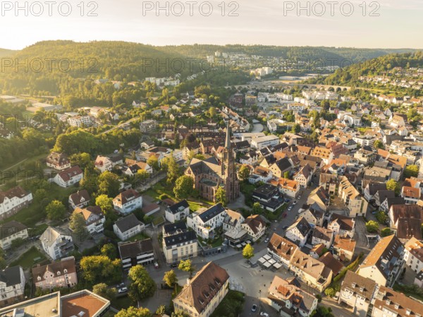 Spacious aerial view of a town with a central church, many houses and hills in the background at sunset, Nagold, Black Forest, Germany, Europe