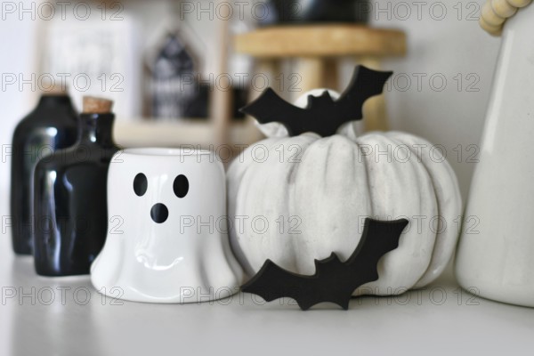 Black and white Halloween decoration with ghost shaped candle, pumpkin, wooden bats and potion bottles